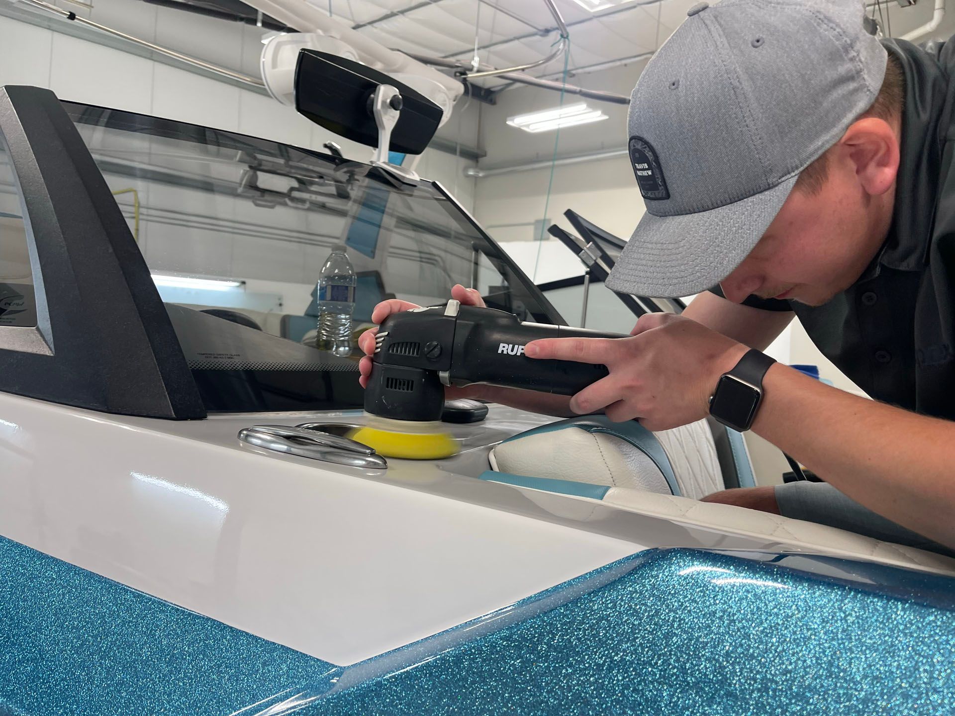 A man is polishing a boat with a machine.