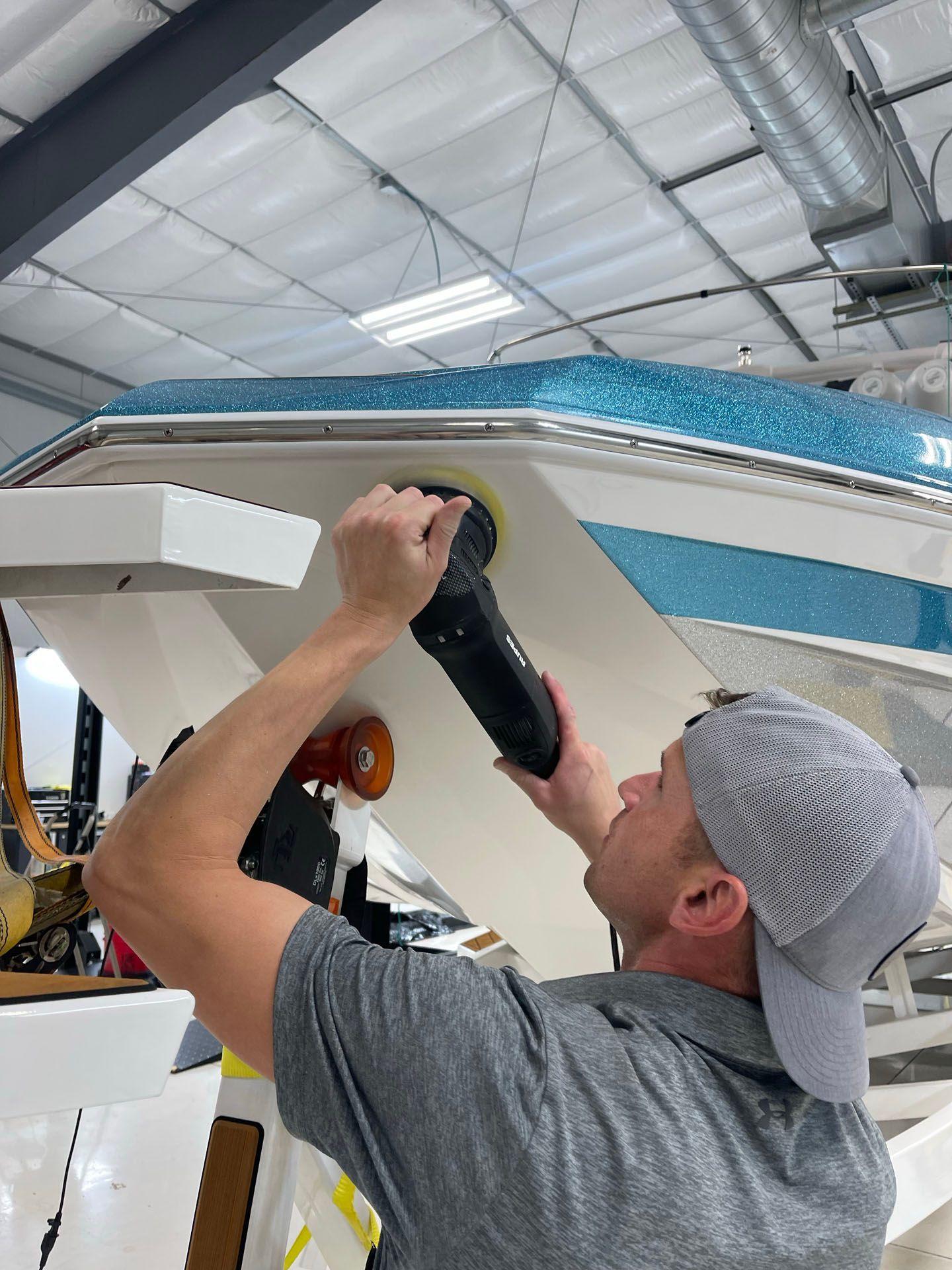 A man is polishing a boat in a warehouse.