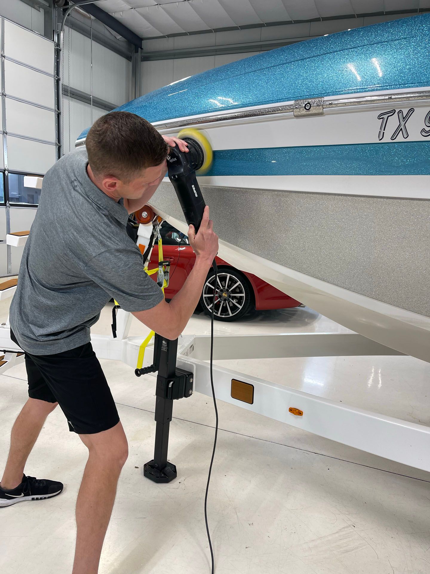 A black car is being worked on by a person in a garage.