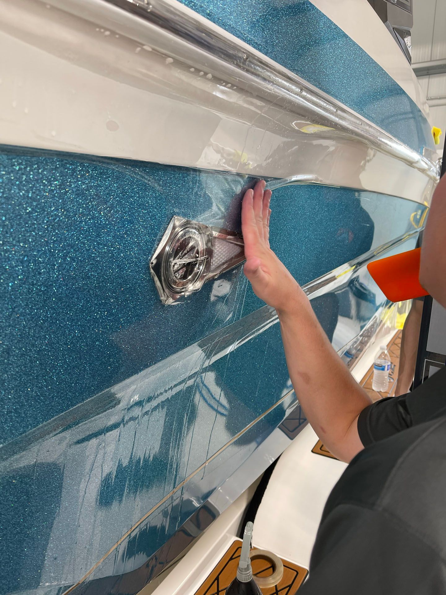 A man is cleaning the side of a boat with a sponge.