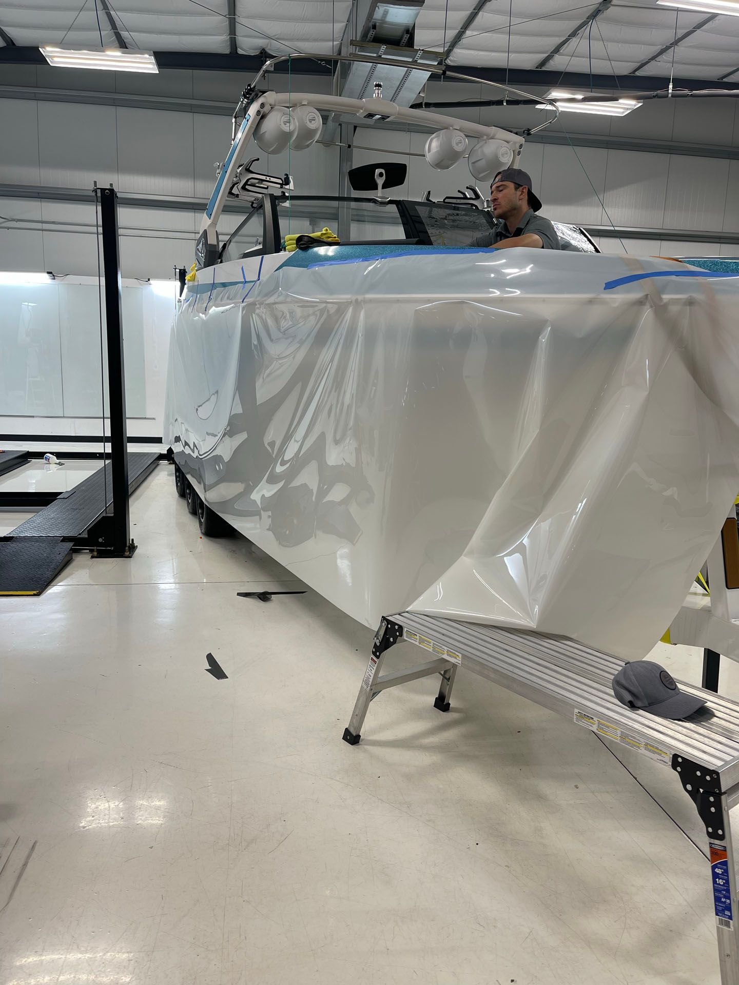 A man is sitting in the cockpit of a boat covered in plastic.