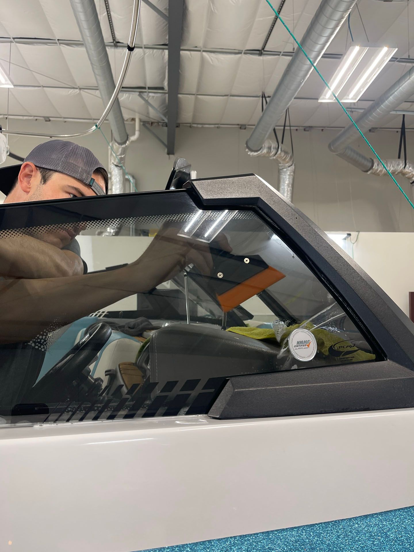 A man is working on a car windshield in a garage.