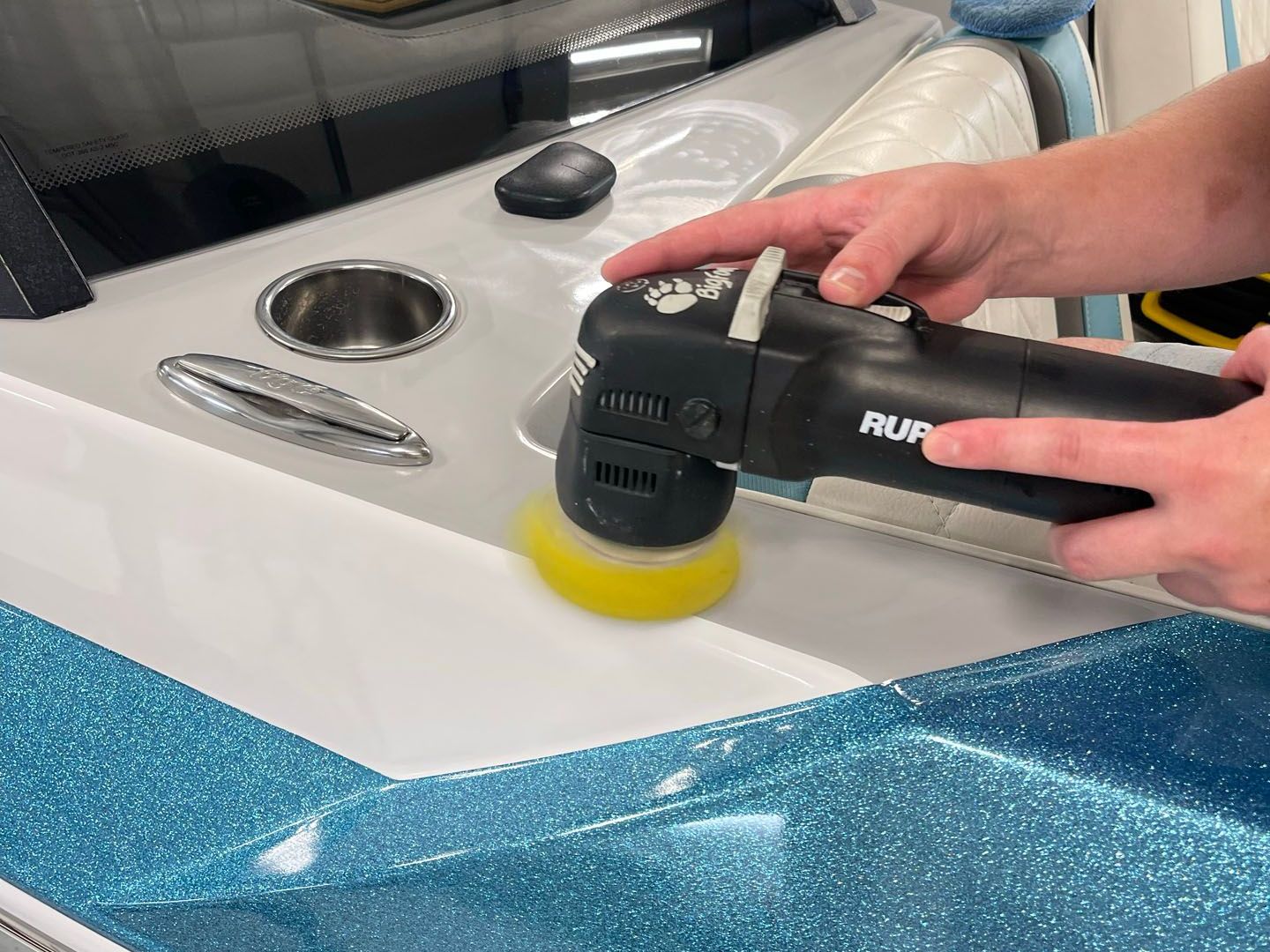 A person is polishing a boat with a machine.