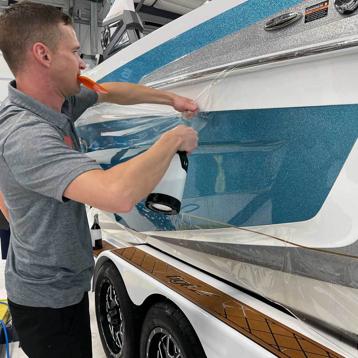 A man is spraying a boat with a spray bottle.