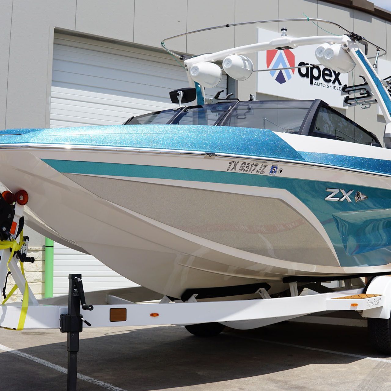 An apex boat is parked in front of a garage