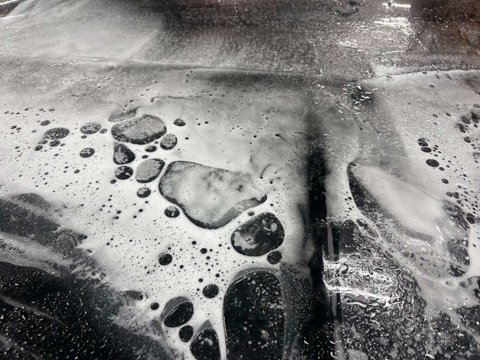 A black and white photo of a soapy surface with bubbles coming out of it.