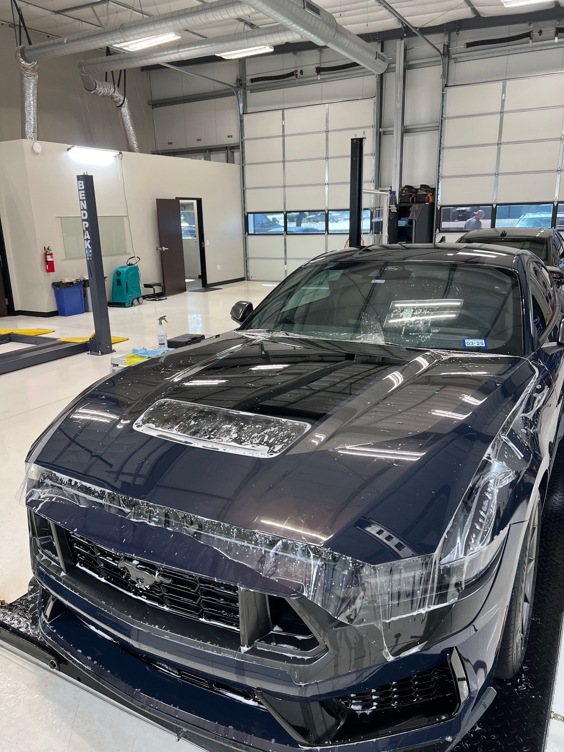 A person is cleaning a car with a blue sponge