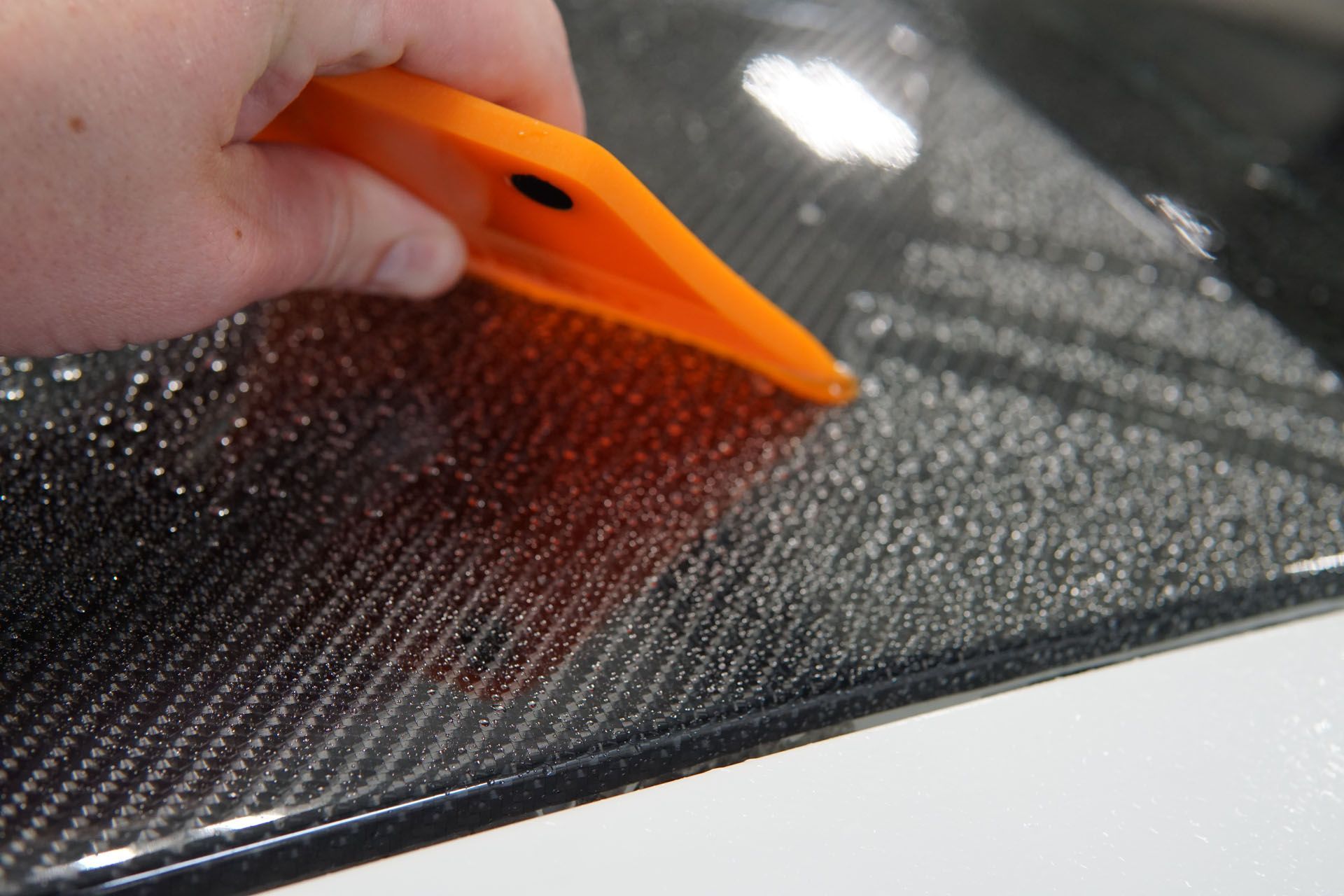 A person is cleaning a car with a blue sponge.