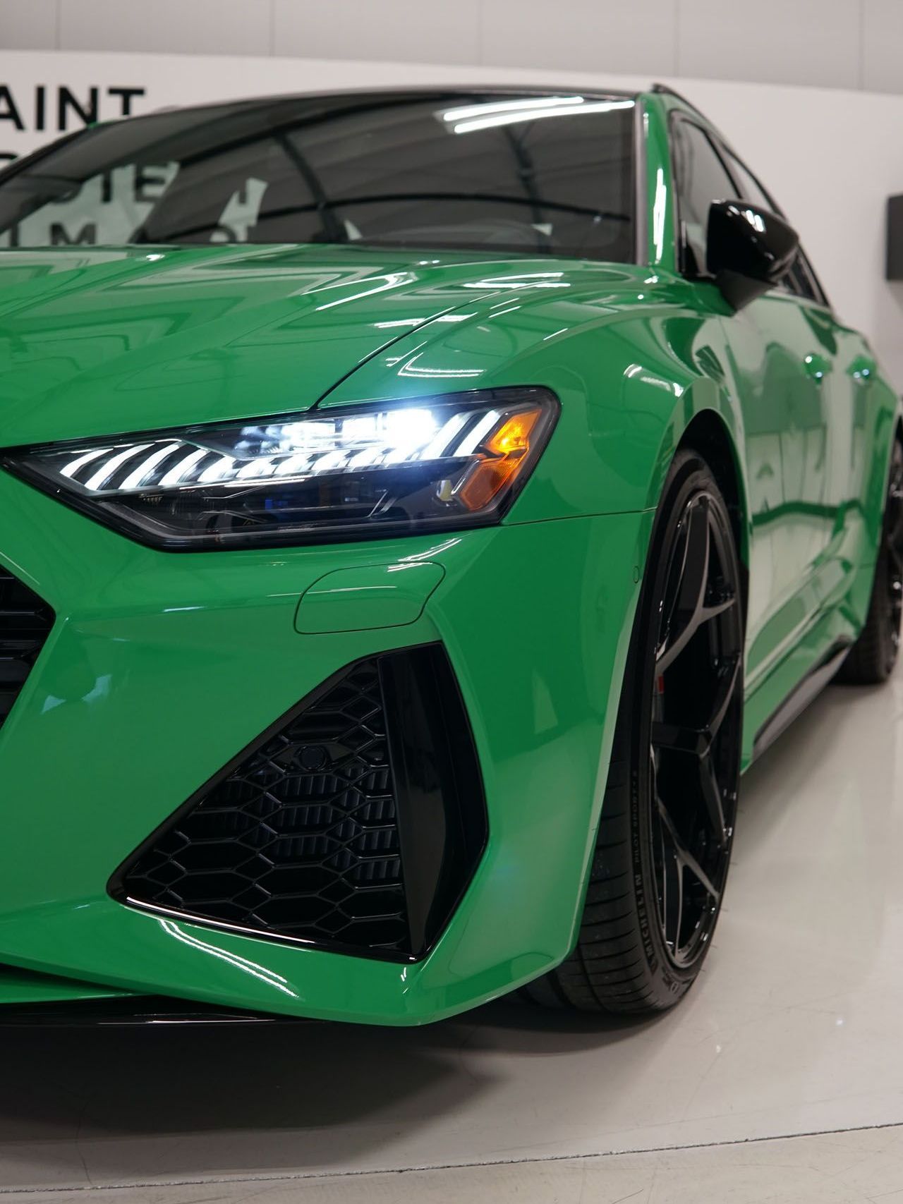 A green car with black wheels is parked in a garage.