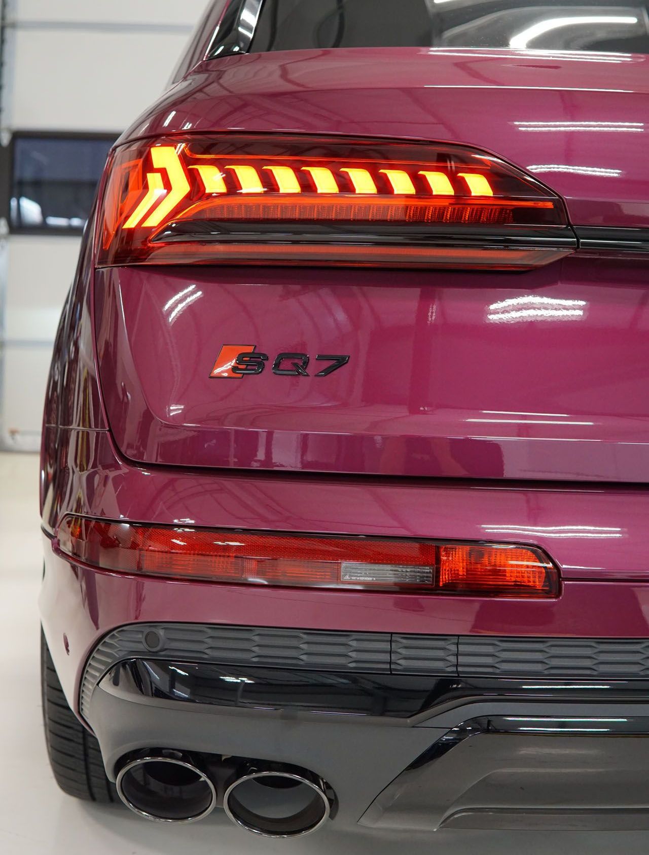 The rear end of a purple audi q7 is shown in a garage.