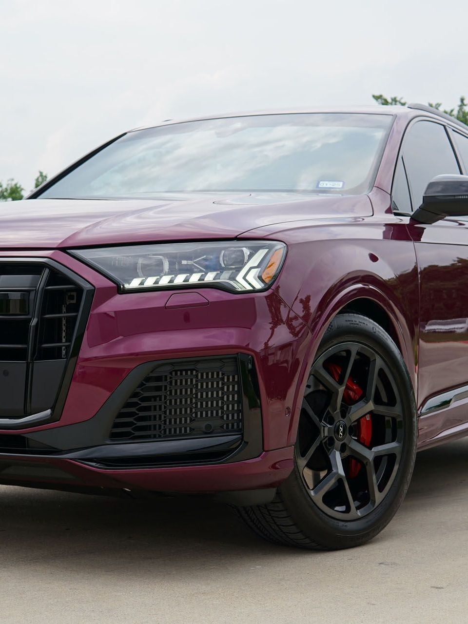 A red audi q7 is parked on the side of the road.