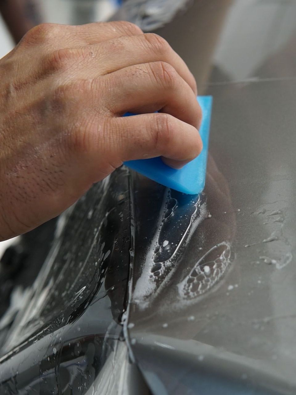 A person is cleaning a car with a blue sponge