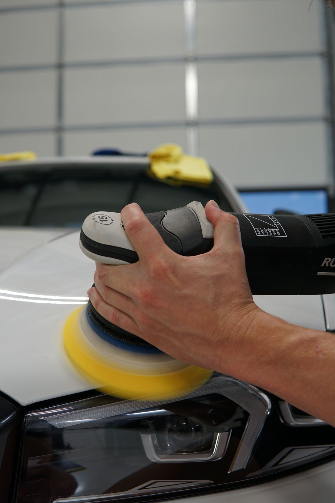 A person is polishing a car with a machine.