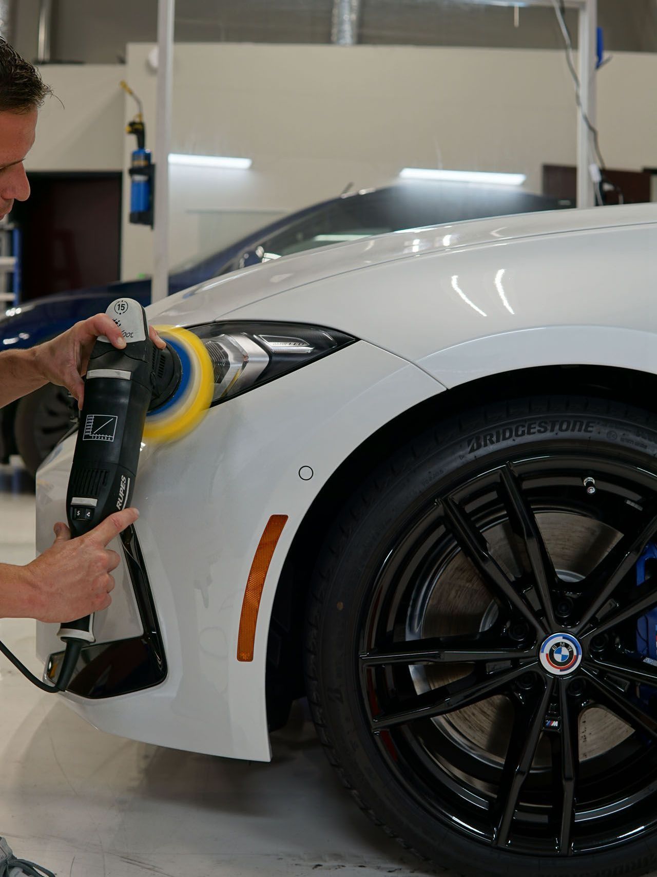 A man is polishing the front of a white car