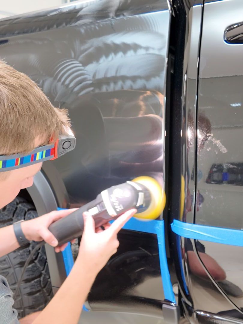 A young boy is polishing the side of a truck