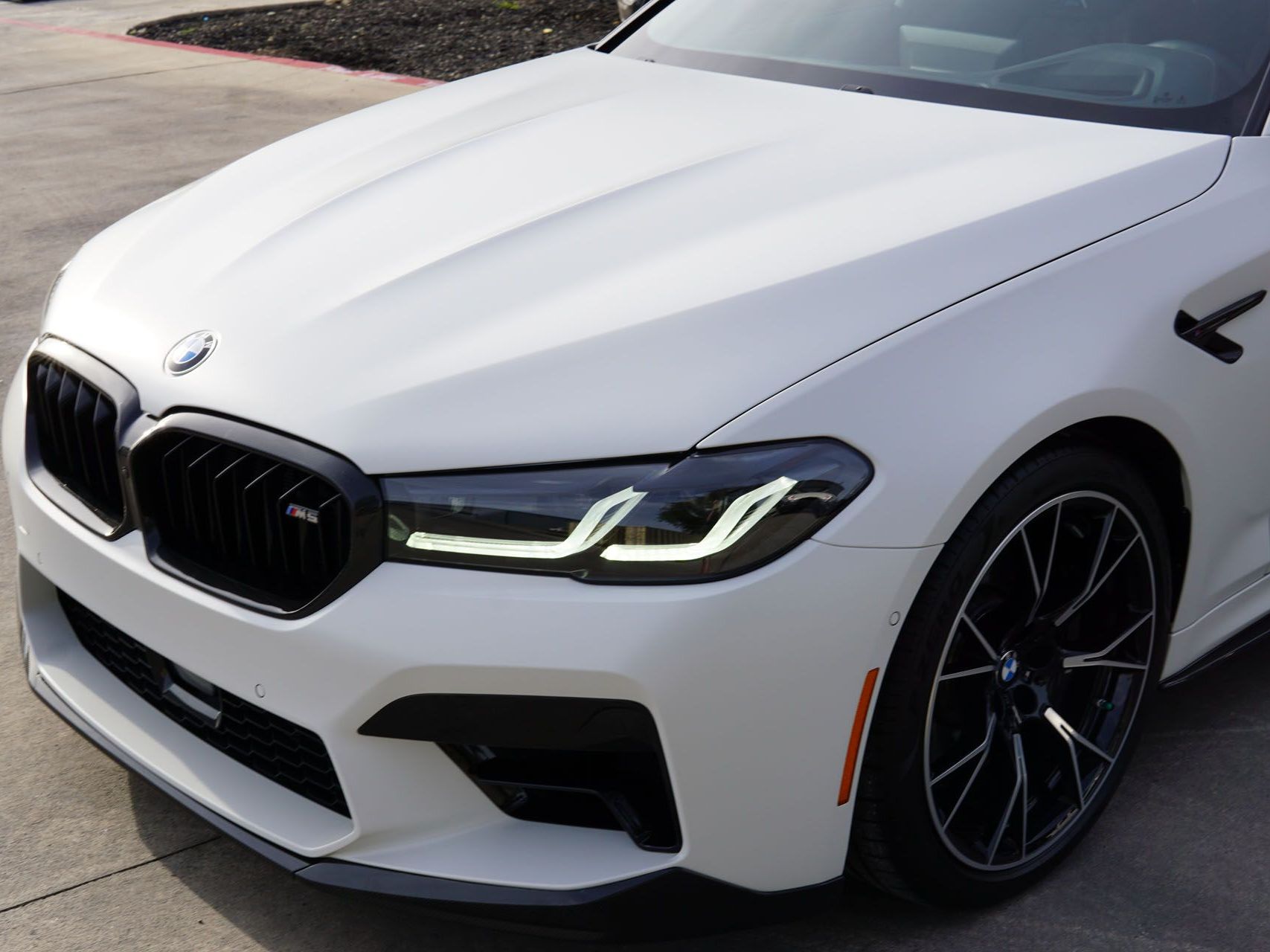 A white bmw is parked on the side of the road