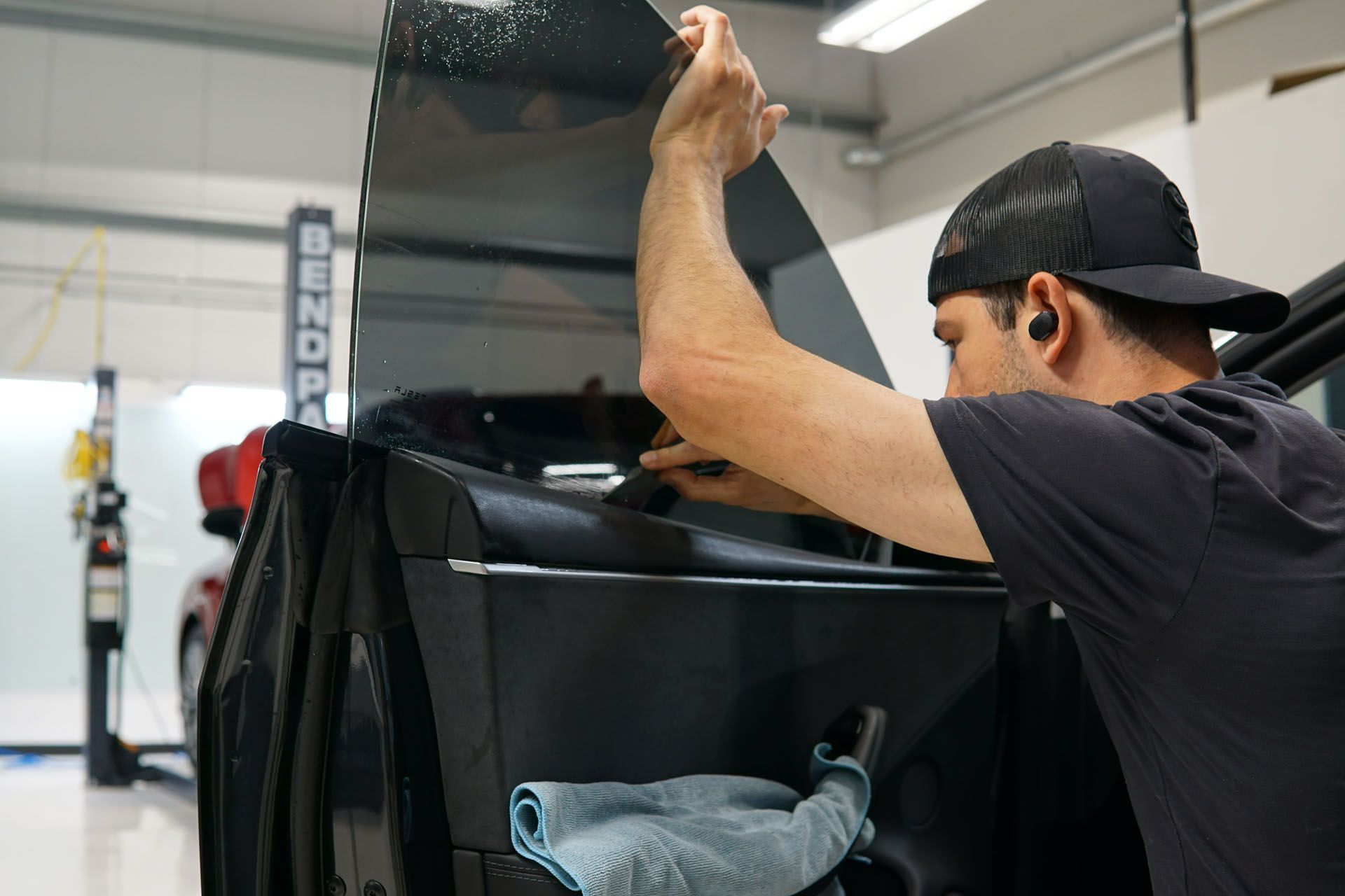 A person is applying tinted glass to a car windshield.