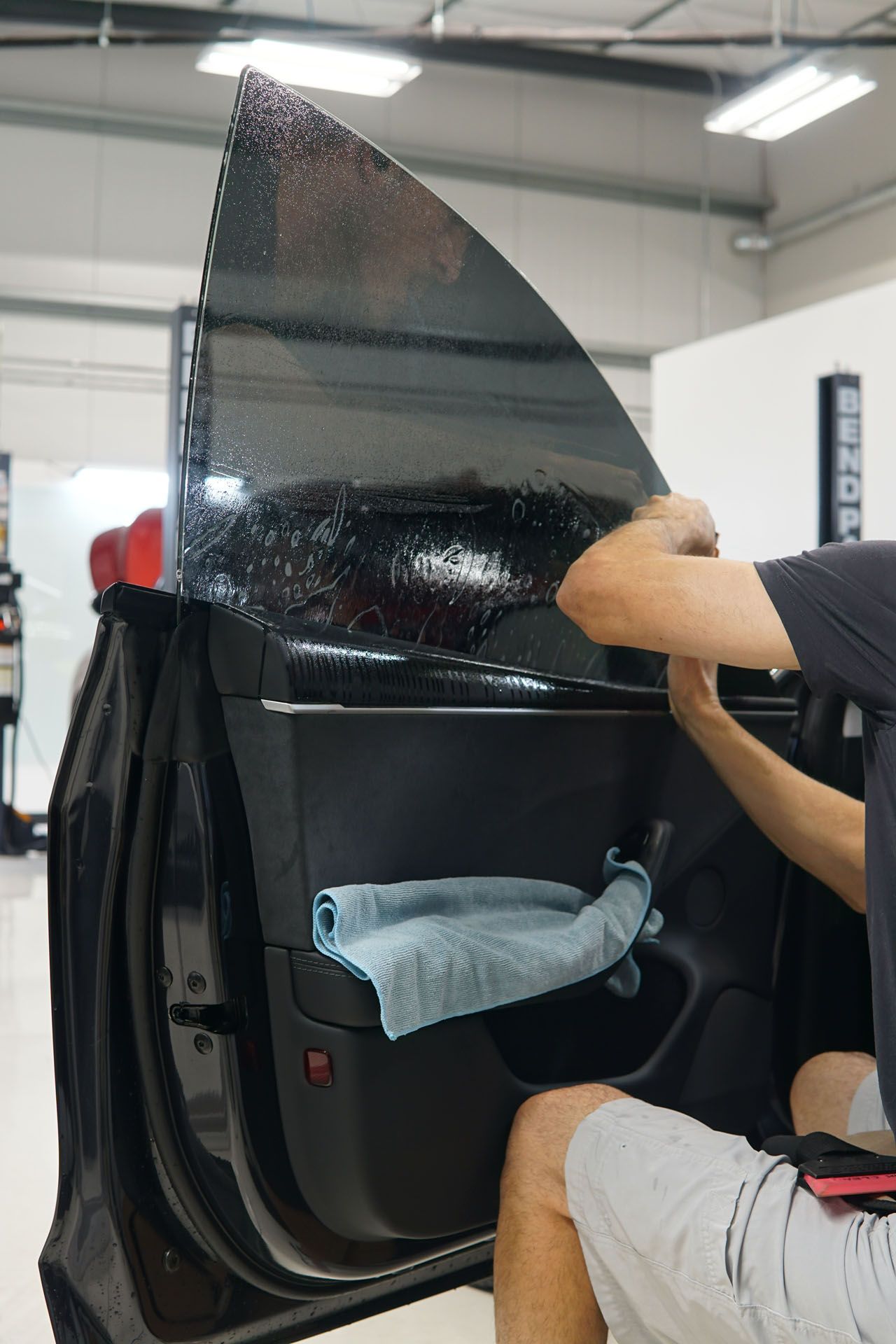 A man is installing window tinting on a car door.