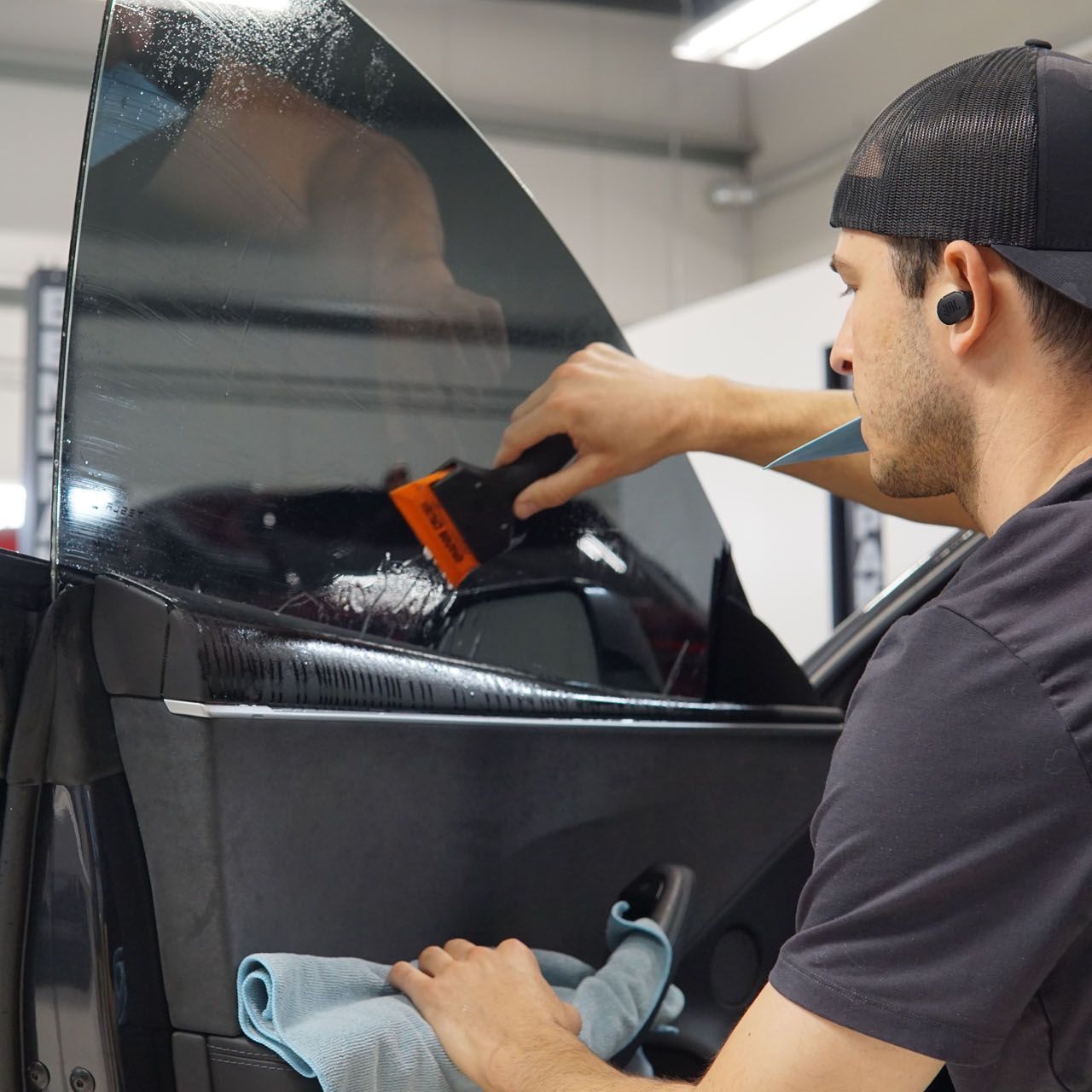 A man is cleaning a car window with a cloth