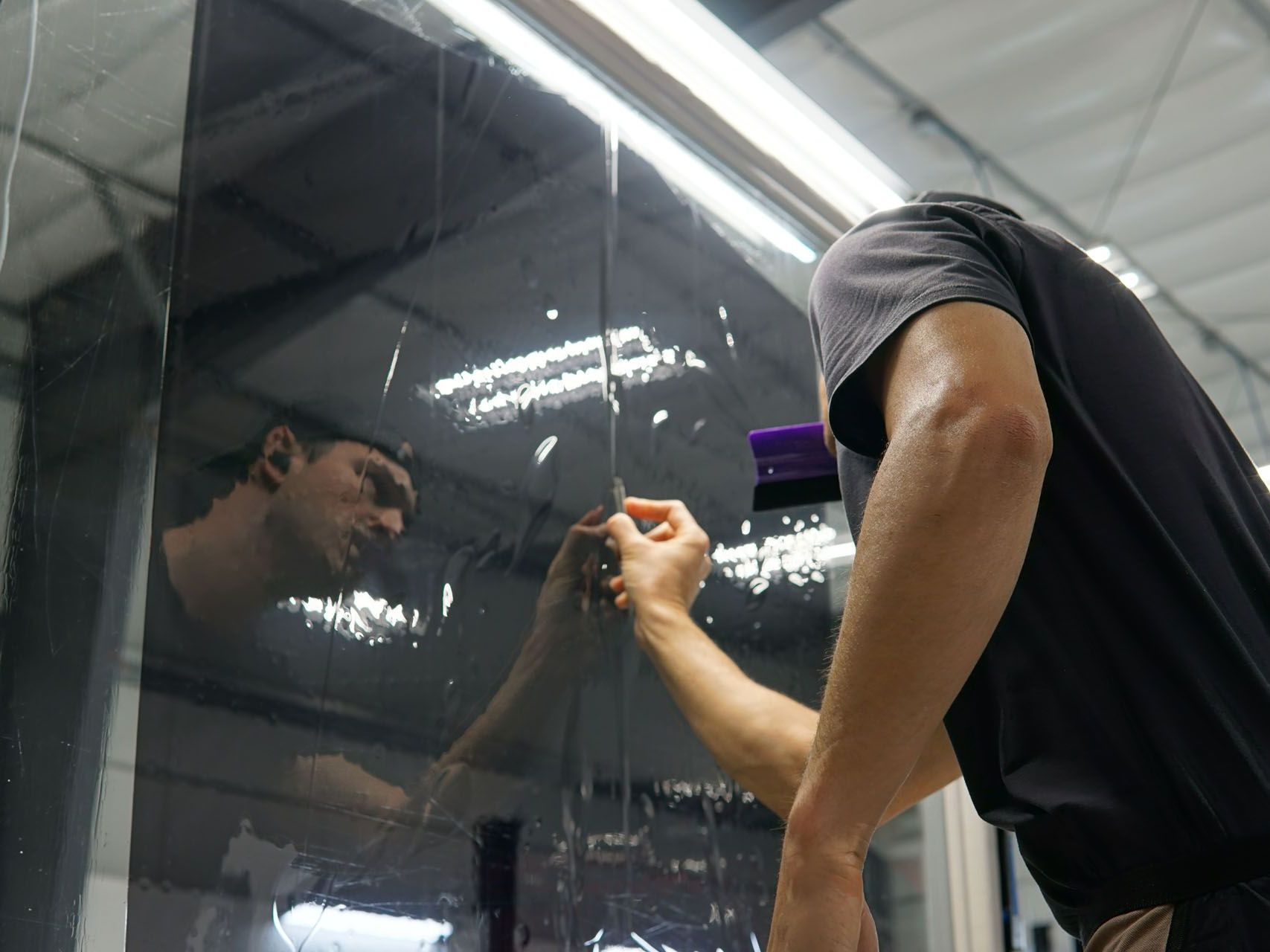 A man is applying tinted glass to a window.