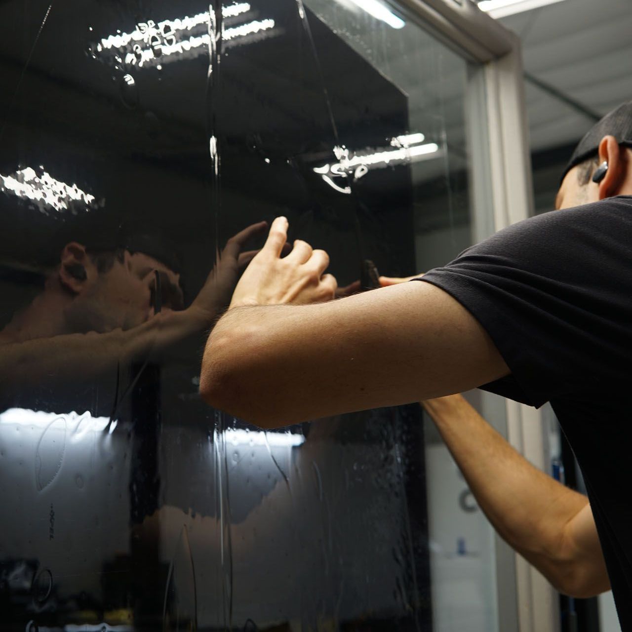 A man is applying window tinting to a car door