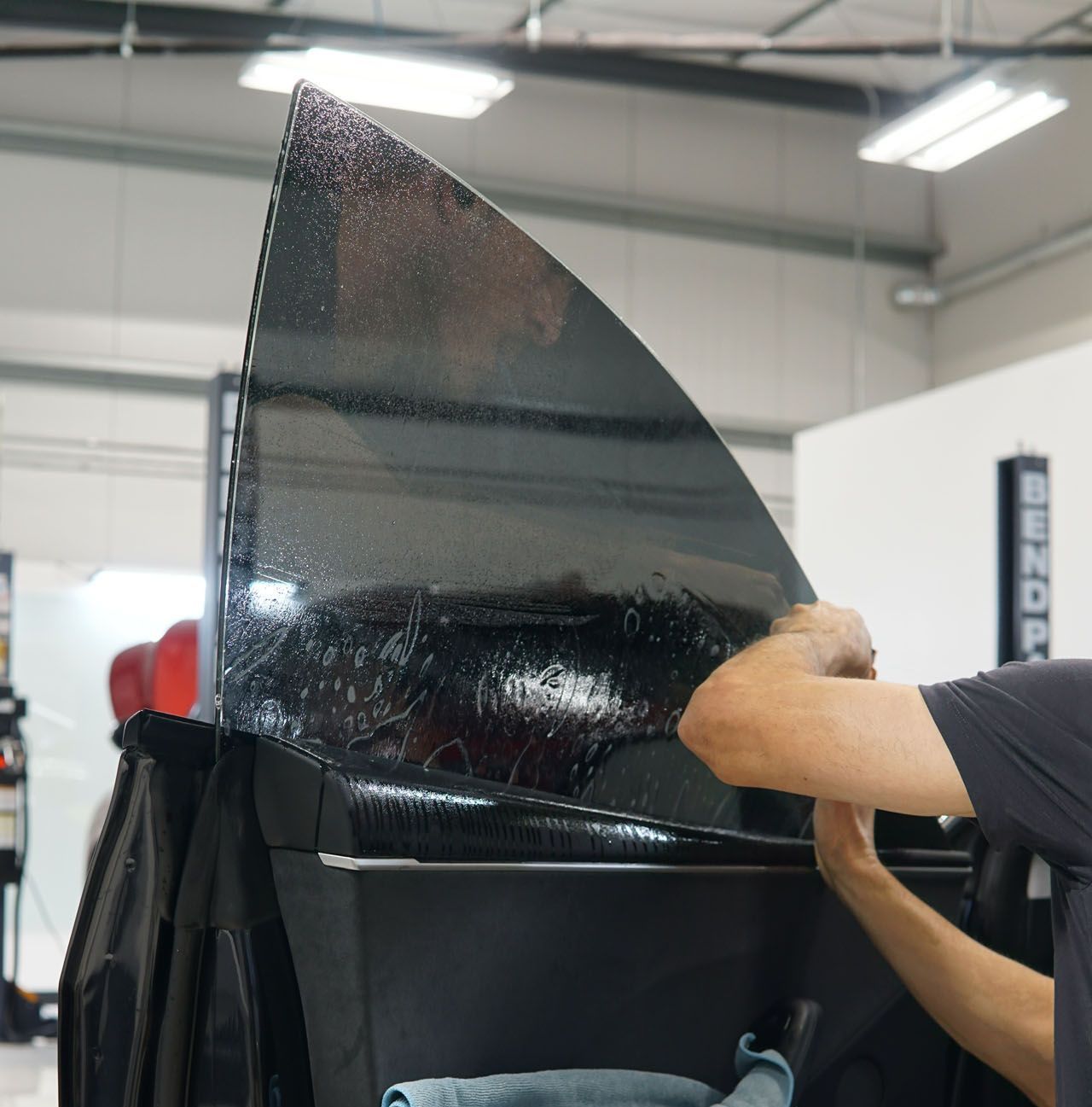 A man is applying window tinting to a car door