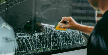 A man is cleaning a window with a sponge.