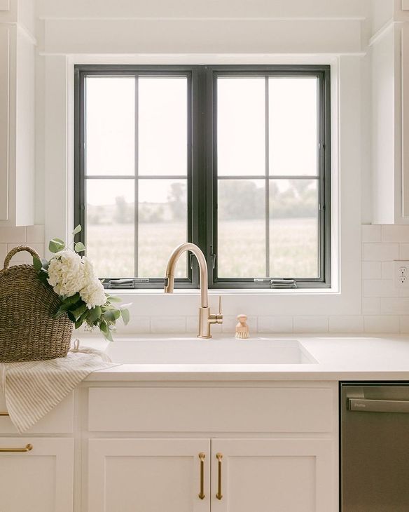 A kitchen sink with a window and a basket of flowers on the counter.