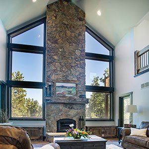 A living room with a large stone fireplace and lots of windows.