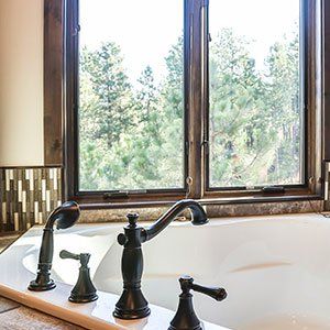 A bathtub with black faucets and a window in a bathroom.