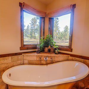 A bathtub is sitting in the corner of a bathroom next to a window.