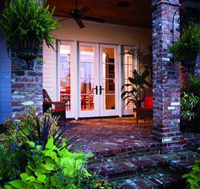 A brick porch with french doors and a ceiling fan
