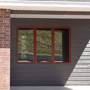 A window on the side of a house with a brick wall.