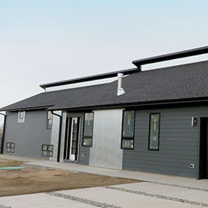 A large gray house with a black roof and a lot of windows.
