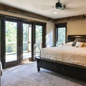 A bedroom with a bed , sliding glass doors and a ceiling fan.