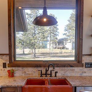A kitchen with a red sink and a large window.