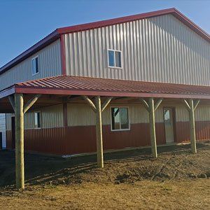 A large metal building with a red roof and a porch.