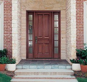 The front door of a brick house with a wooden door