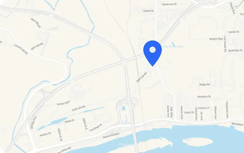 A blue location pin marking an intersection on a light-colored map showing roads, a river, and nearby street names.
