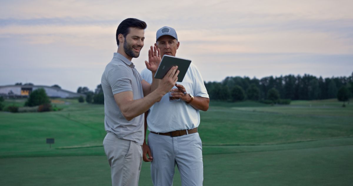 Two men on a golf course using a tablet