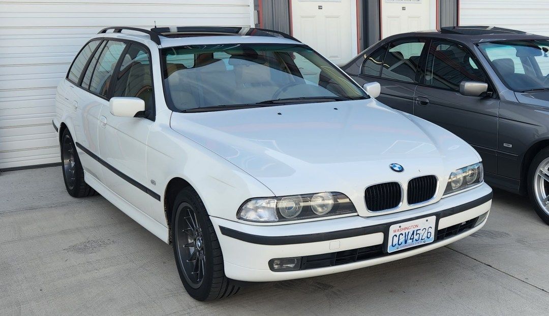 A white bmw is parked next to a black car in a garage. | Bavarian Auto Clinic