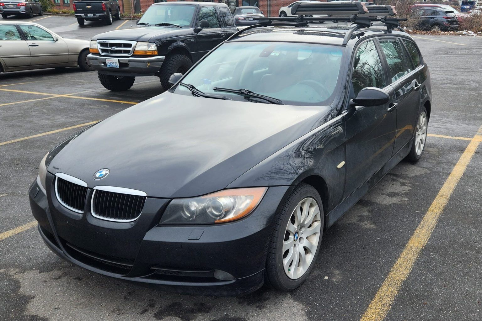 A black bmw with a roof rack is parked in a parking lot. | Bavarian Auto Clinic