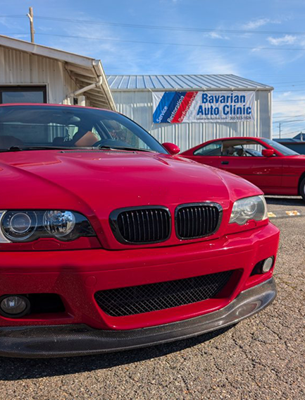 A red bmw is parked in front of a bavaria auto clinic. | Bavarian Auto Clinic