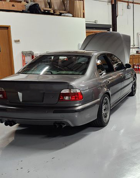 A gray car with the hood up is parked in a garage | Bavarian Auto Clinic
