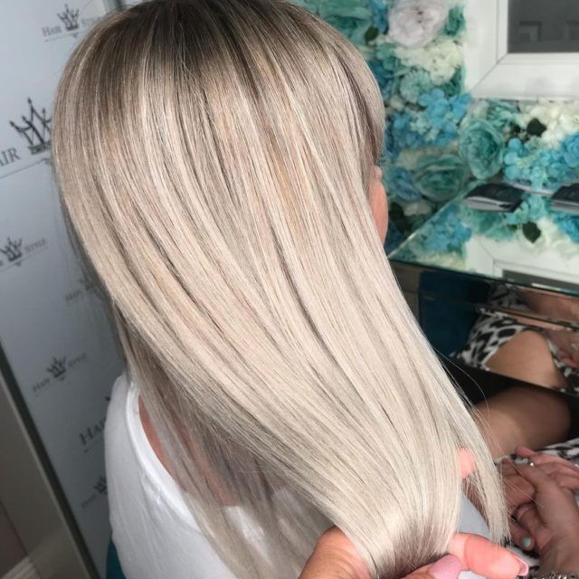 Woman with straight, platinum blonde hair styled.