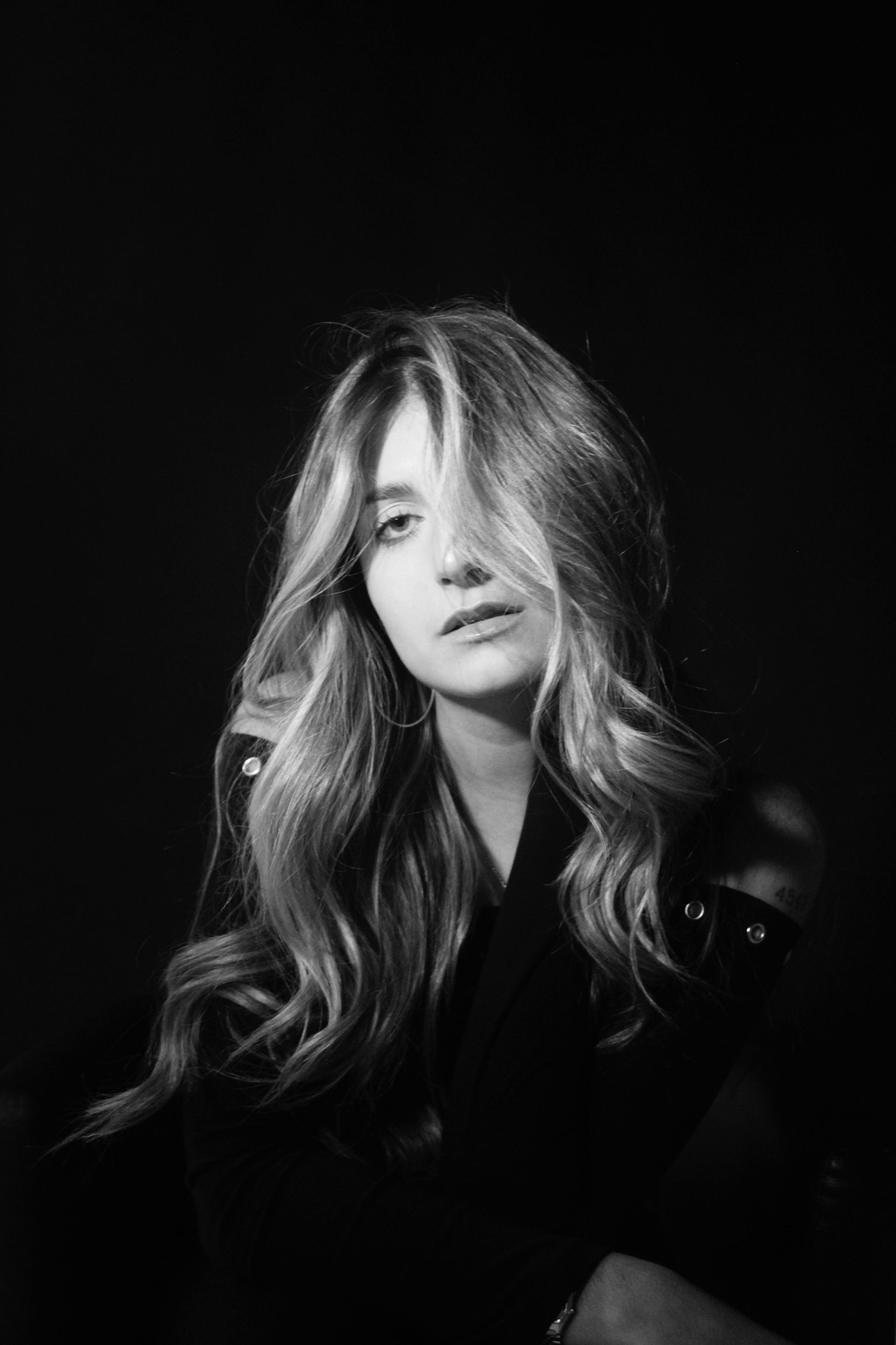 Woman with glowing skin, hand on cheek, lit by sunlight.