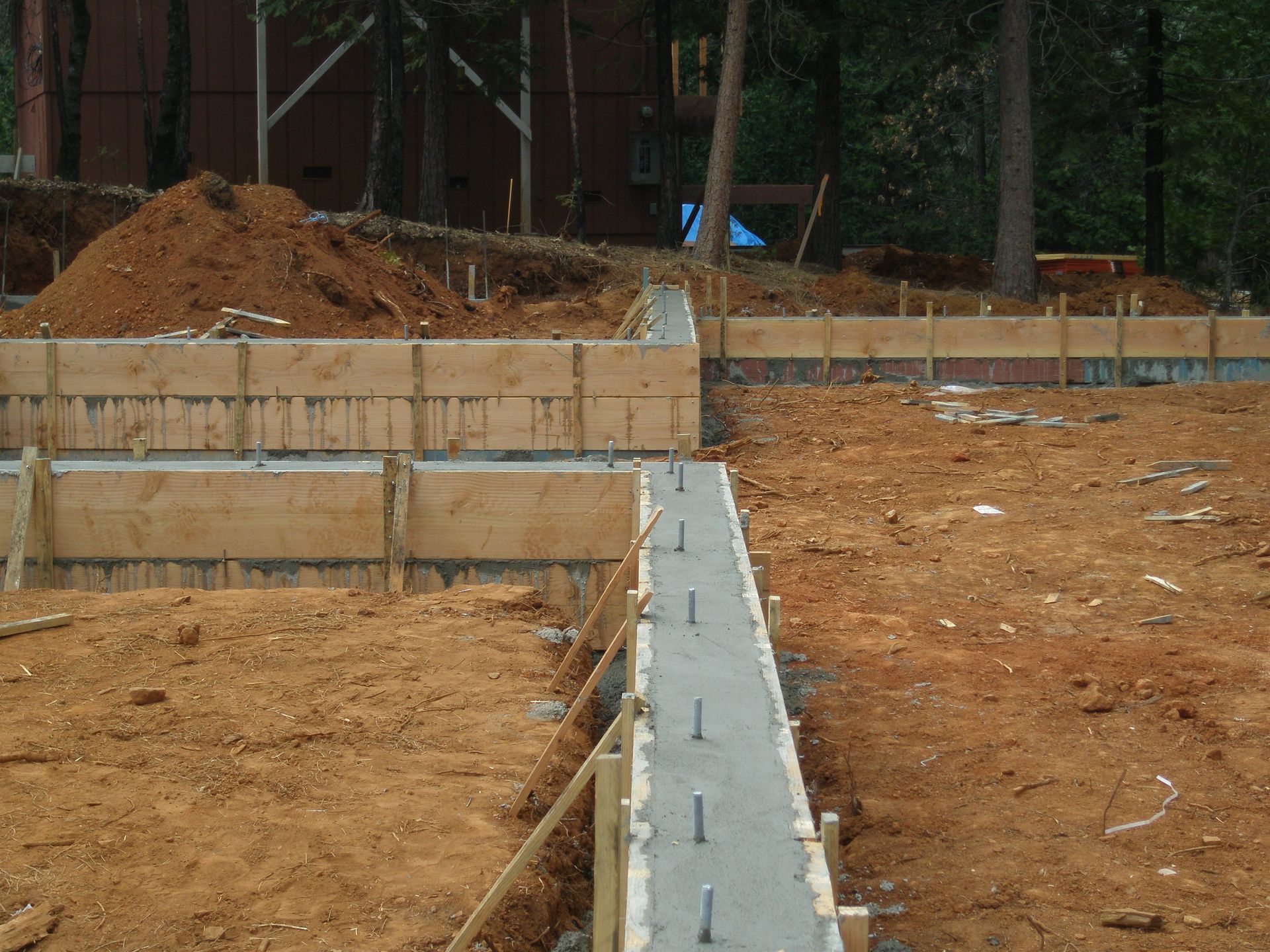 Three people spread wet concrete on a driveway. Houses and a car are in the background.
