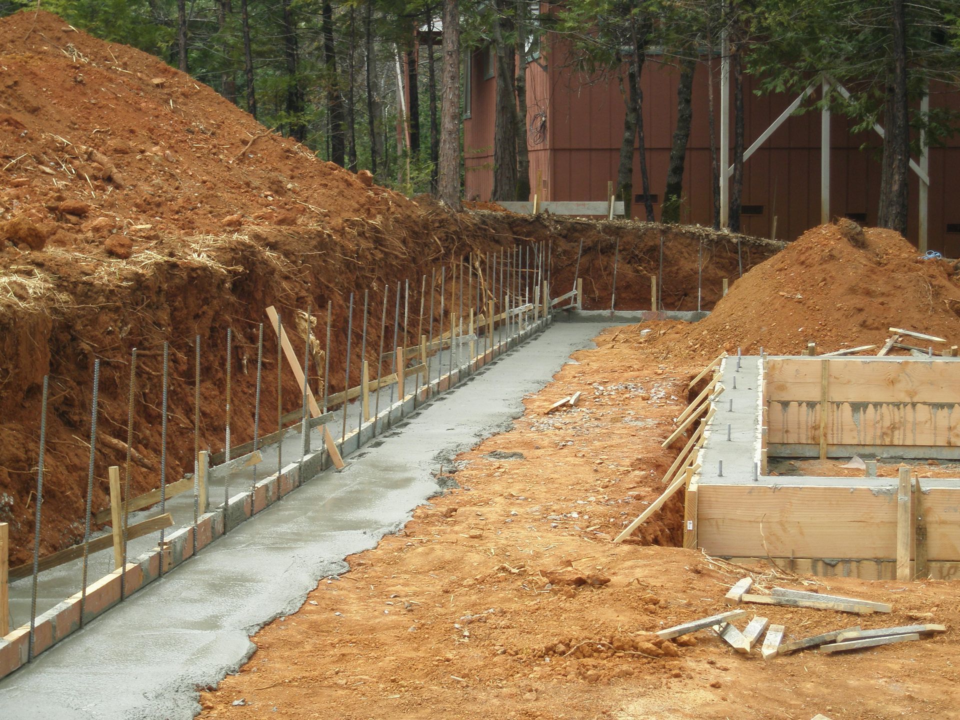 Man in a safety vest smoothing wet concrete with a screed tool. Construction site in a residential neighborhood.