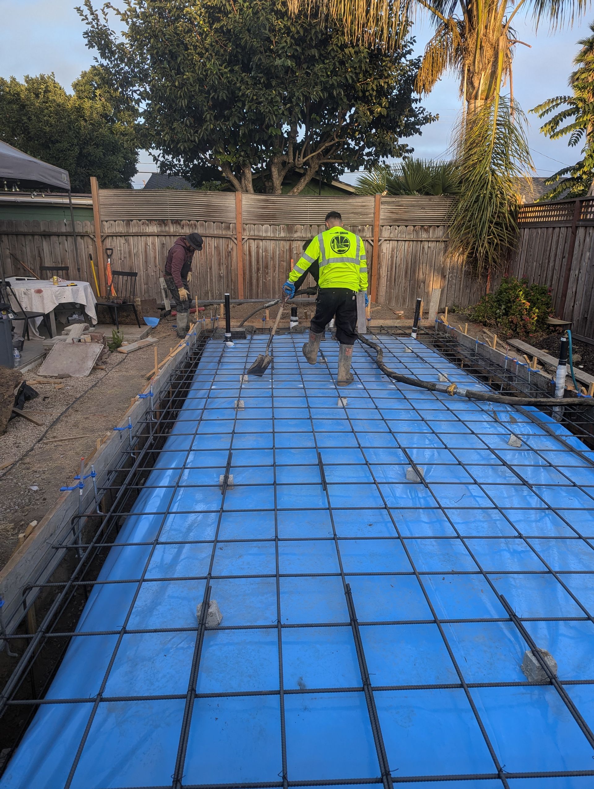 Construction site foundation, with exposed concrete and wooden formwork, near a coastline.