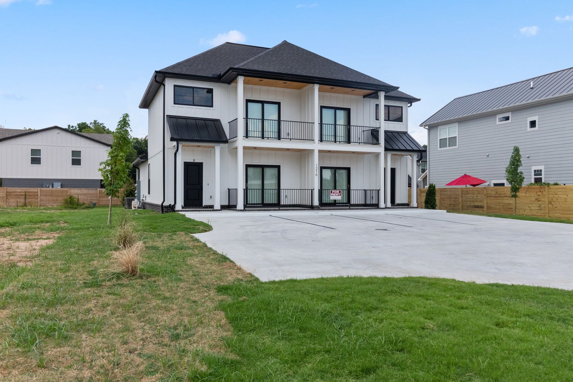 A large white house with a black roof is sitting on top of a lush green field.